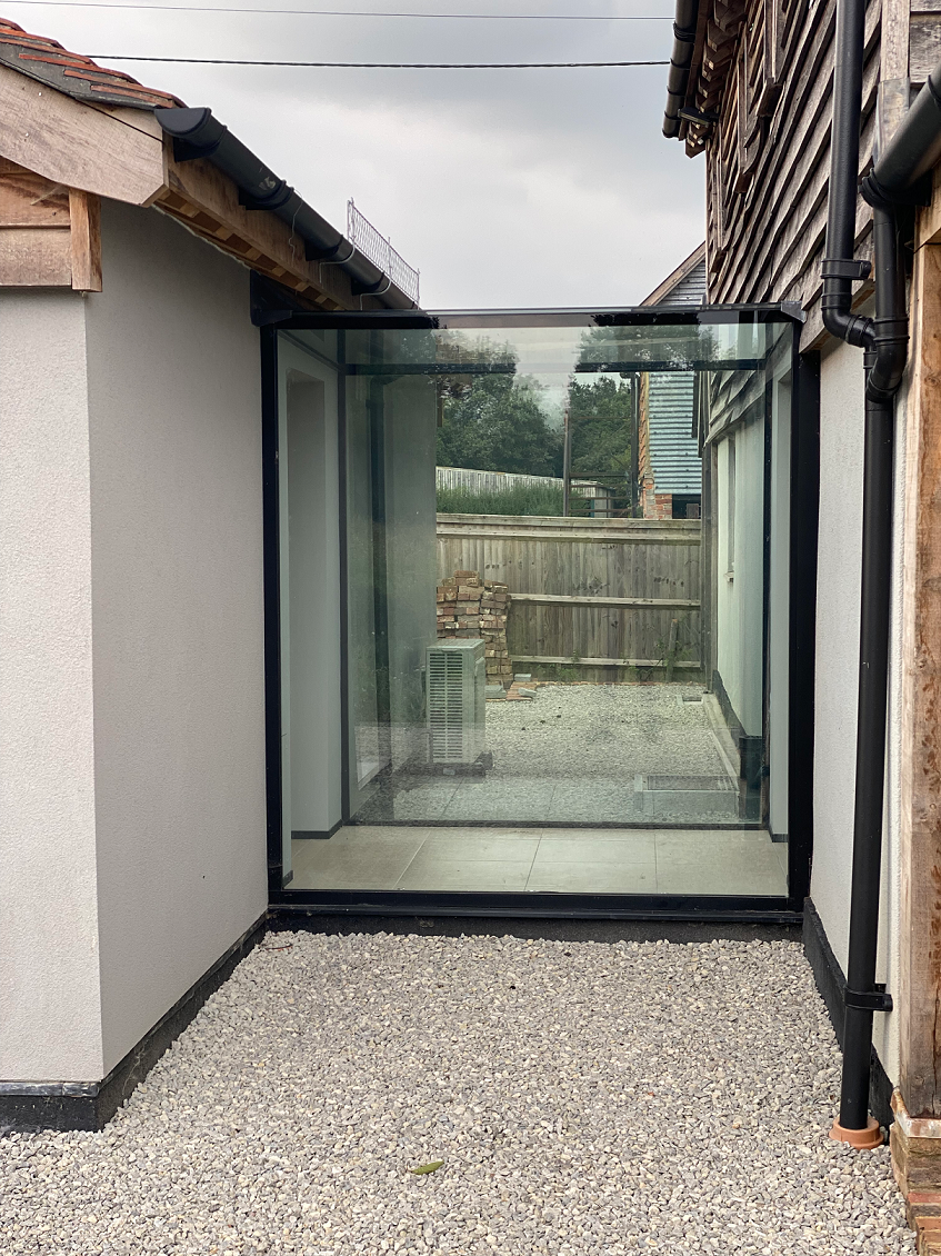 Frameless Glass Structure Linking Barn with New Building in West Sussex